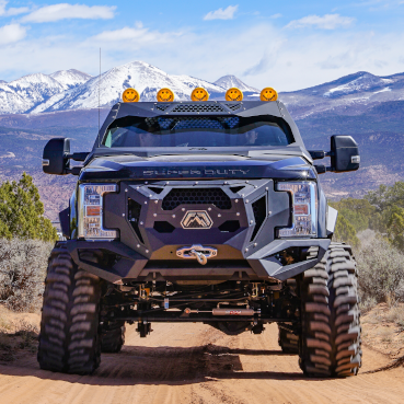 Lifted heavy-duty truck with upgraded steering and suspension components driving off-road, representing Dodge and Ford steering system applications.