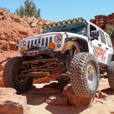 White PSC Jeep climbing a rock. 