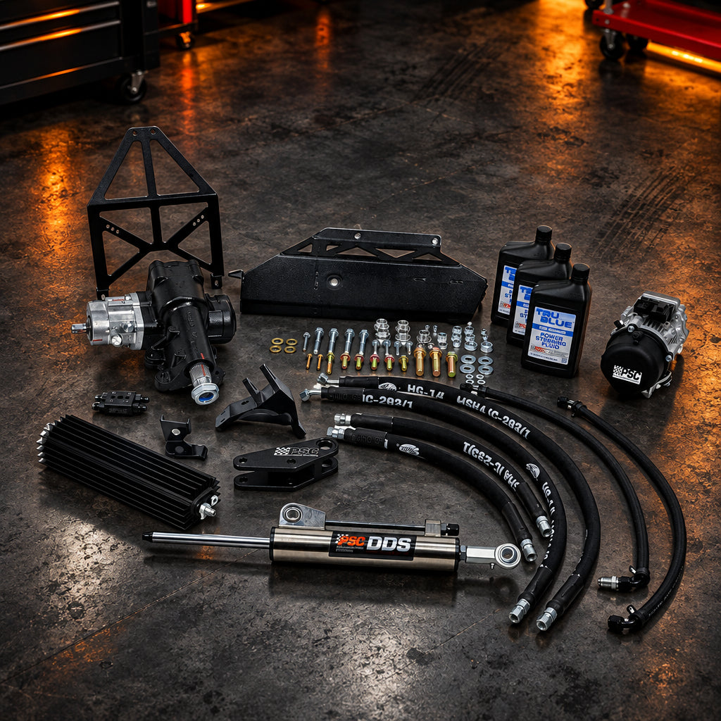 A complete vehicle suspension and steering kit laid out on a white background, including a black frame, shock absorber, control arms, hoses, steering knuckle, motor, brackets, and small hardware.