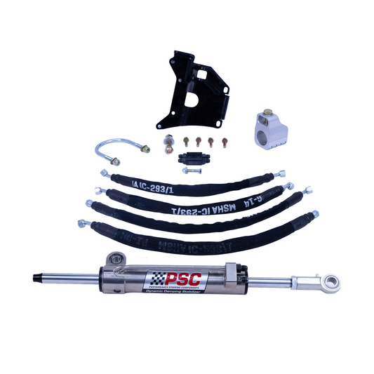 A PSC suspension lift kit laid out on a white background, including a black shock absorber, black leaf springs with white lettering, mounting brackets, a white control module, small hardware, and a braided metal hose.