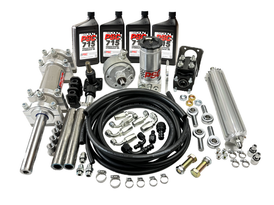 Full hydraulic steering kit displayed on a white background, including hydraulic cylinder, pump, reservoir, hoses, fittings, clamps, mounting hardware, fluid cooler, and bottles of PSC 715 Power Steering Fluid.