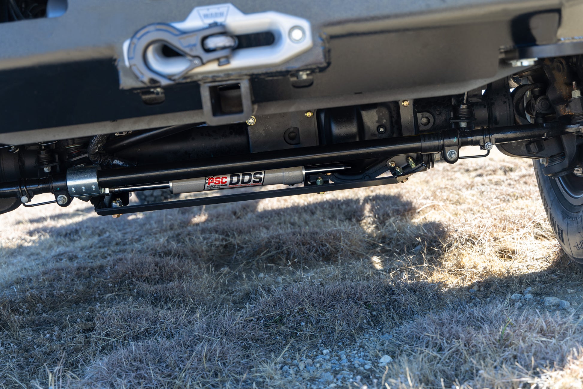 Close-up of a white F550's front end (focusing on the PSC DDS® and front steering axel) on a grassy surface. 