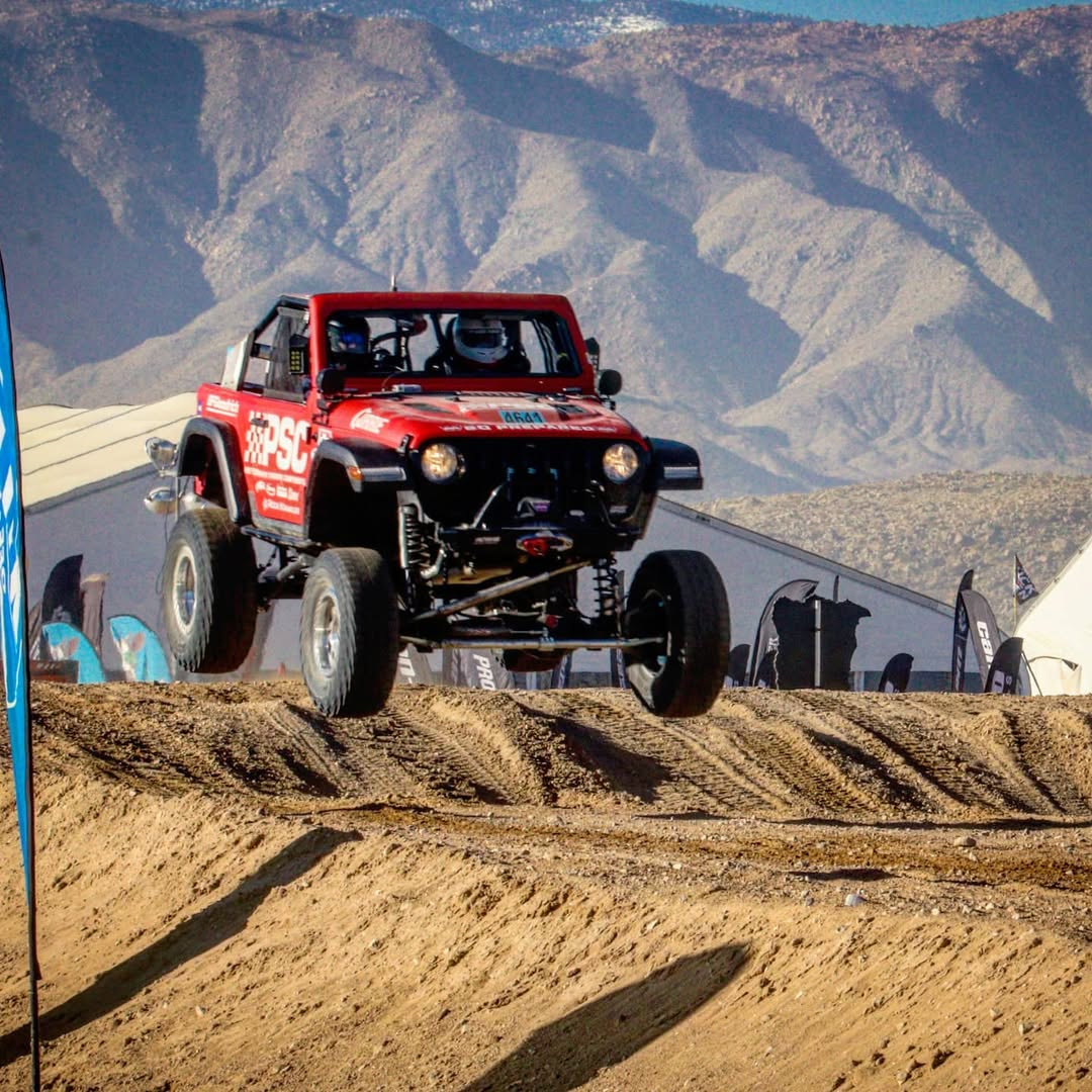 PSC race rig in King of the Hammers 2017. Featuring the red 4641 rig jumping on a dirt path with mountains in the background. 