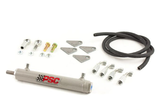 PSC cylinder assist kit laid out with a hydraulic assist cylinder, welded mounting tabs, high-pressure hose, rod ends, hardware and hose fittings designed to add steering assist for off-road vehicle