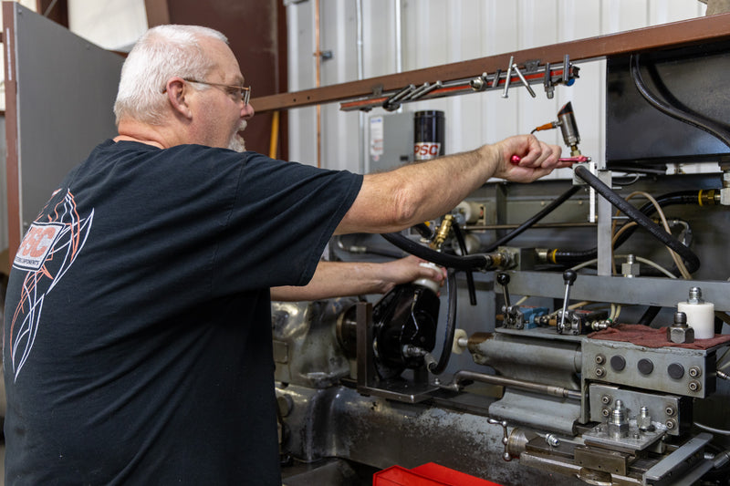 Tim S a PSC technician adjusts hydraulic equipment while testing a steering unit on a shop machine, capturing the hands-on skill and mechanical expertise involved in assembling and verifying precision steering components used in demanding off-road, Jeep and truck environments.