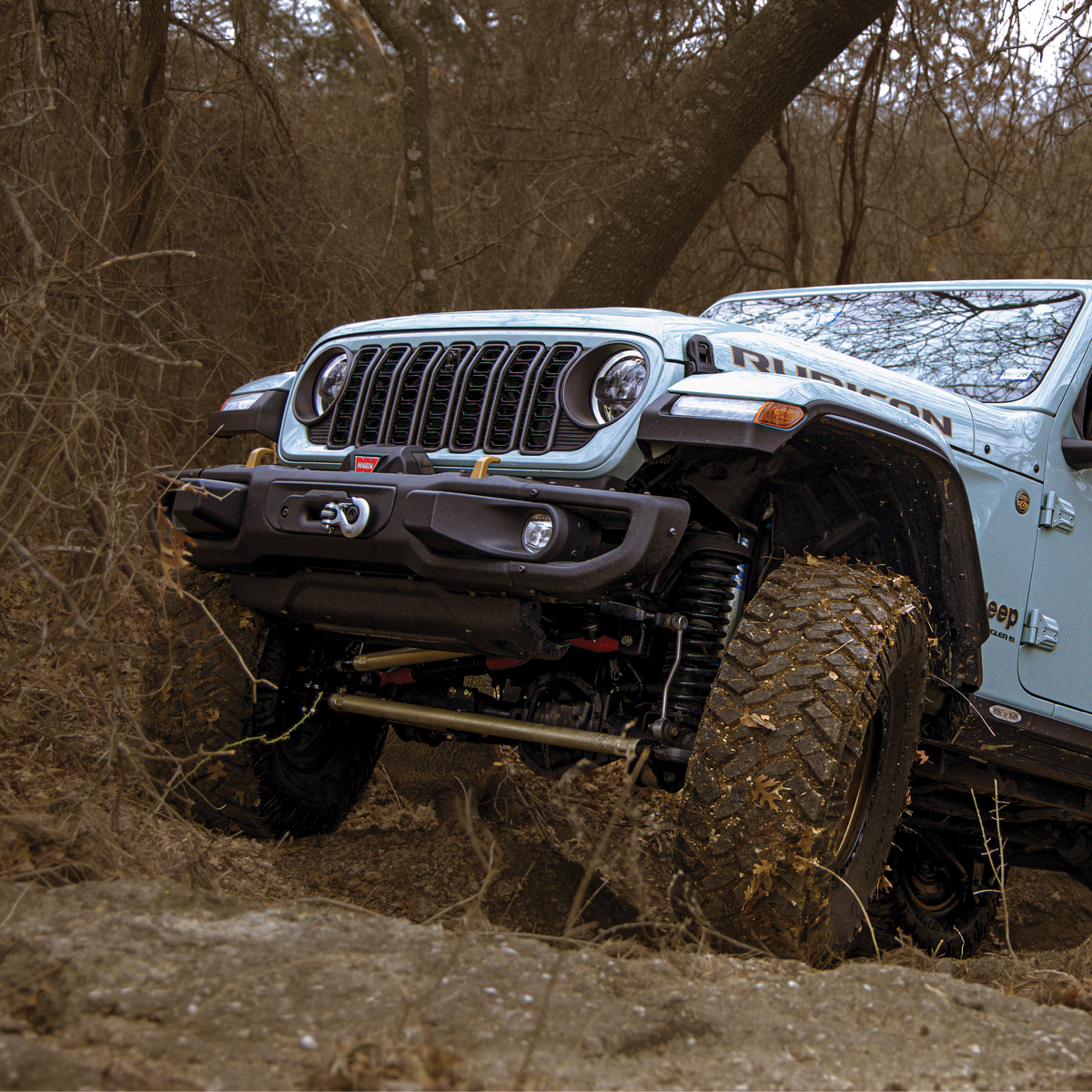 Jeep Wrangler driving through a muddy forest
