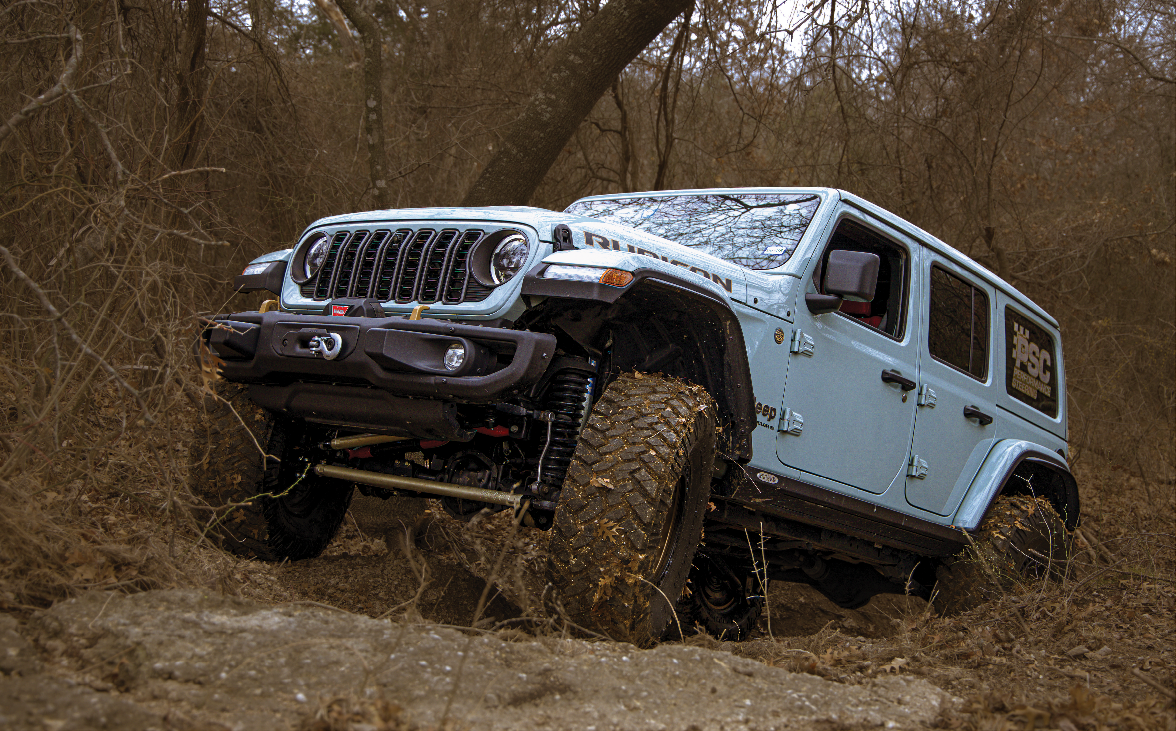 Jeep Wrangler driving through a muddy forest