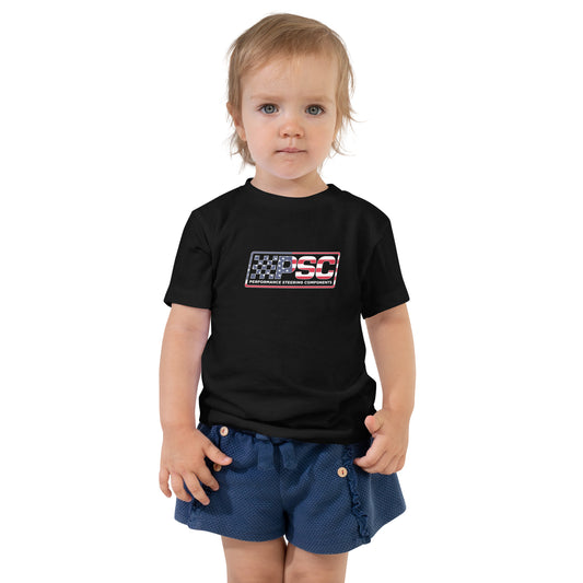 A little girl is wearing a black toddler t-shirt with PSC logo featuring a patriotic overlay and white border. She is featured on a white background.