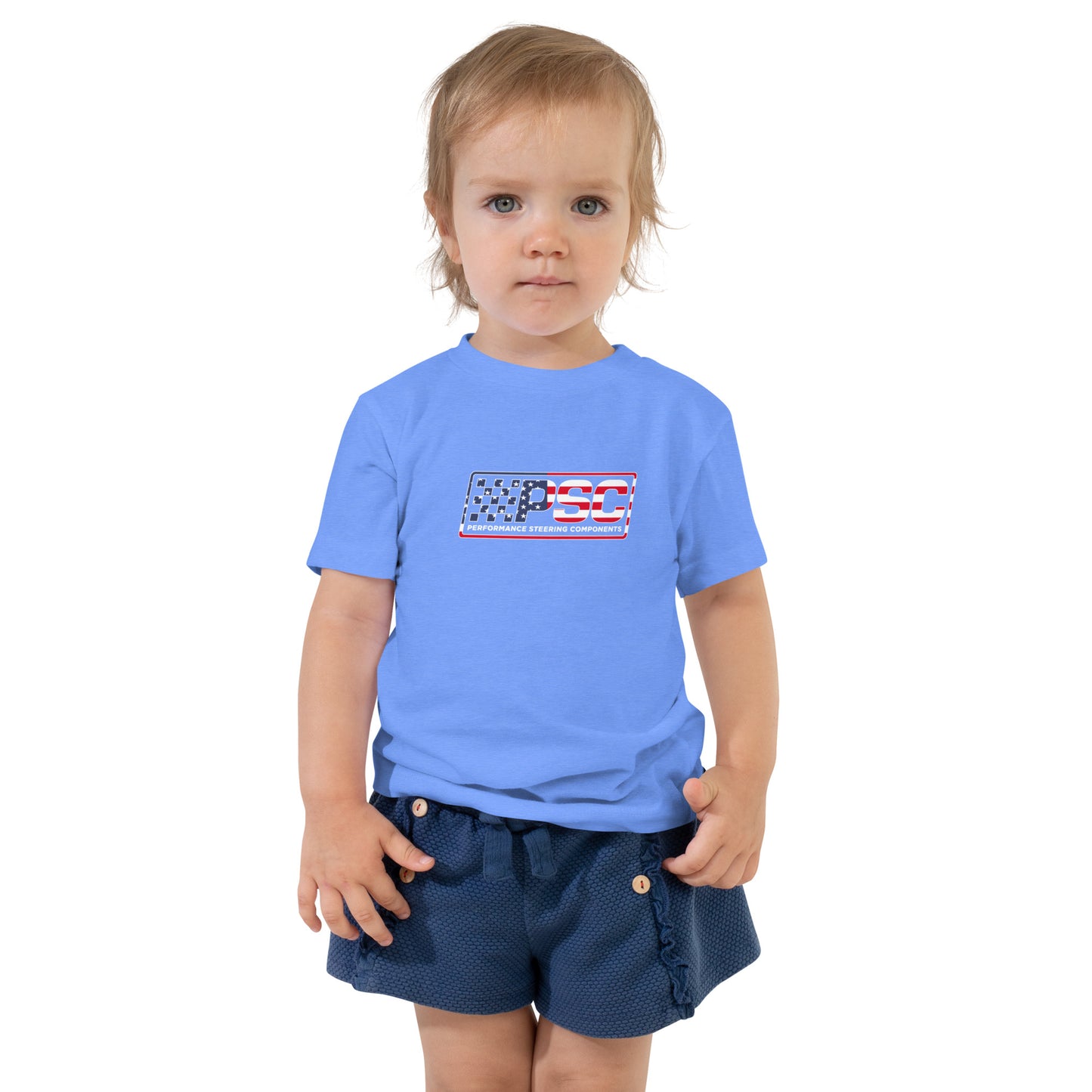 A little girl is wearing a heather Columbia blue toddler t-shirt with PSC logo featuring a patriotic overlay and white border. She is featured on a white background.