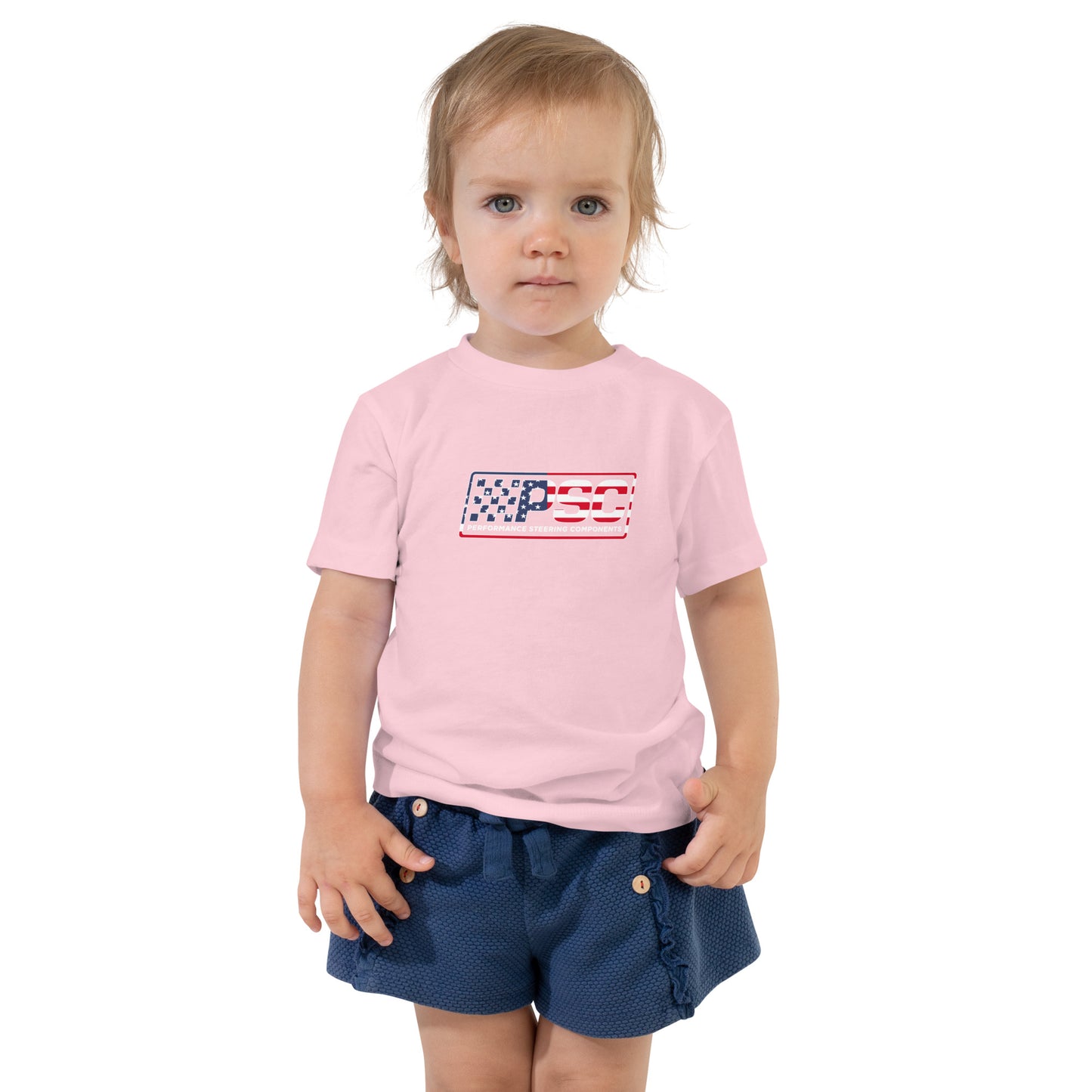 A little girl is wearing a light pink toddler t-shirt with PSC logo featuring a patriotic overlay and red border on a white background. 