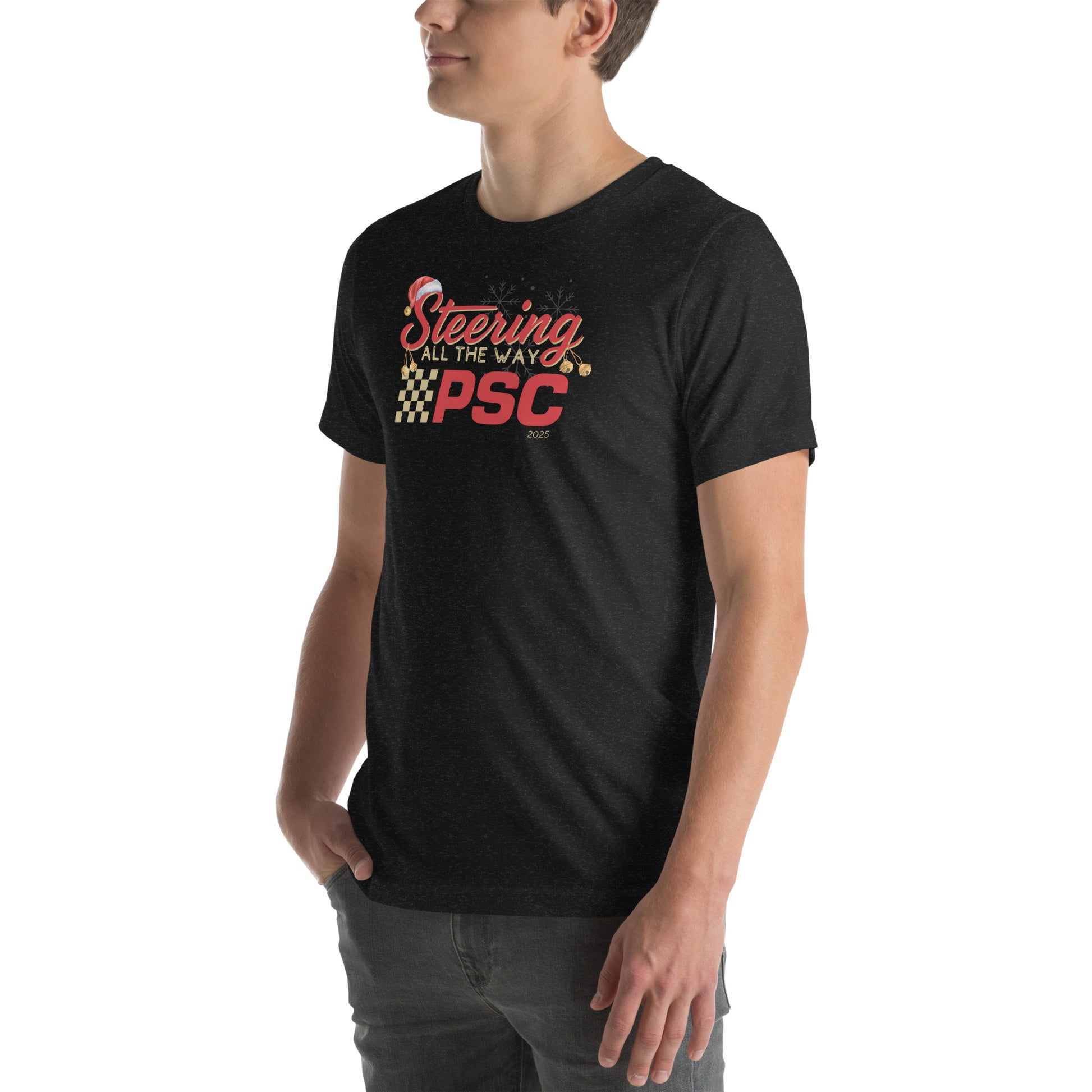 Angled front view of an adult model wearing a heather black short-sleeve T-shirt with a PSC logo and the phrase ‘Steering All the Way PSC 2025’ printed across the chest in red and gold lettering. There is a Santa hat on the "S" in steering, bells handing off the bottom of the "S" and "g" in steering and translucent snowflakes in the background as well as "2025" right bottom corner offset. He is facing the left frame of the image.