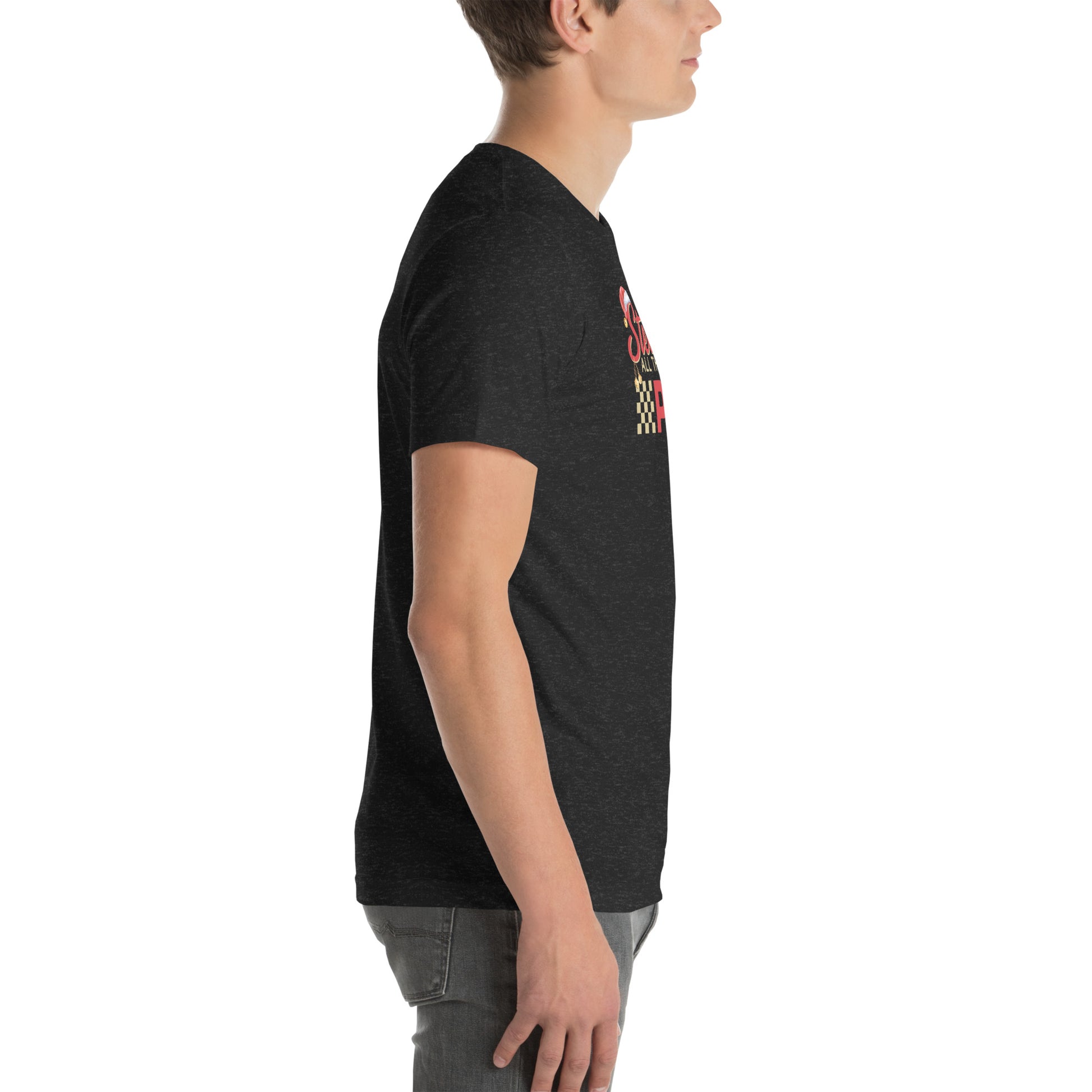 Side view of an adult model facing the right edge of the screen wearing a heather black short-sleeve T-shirt you can see the edge of a red and gold design on the front of the shirt. The background is white.