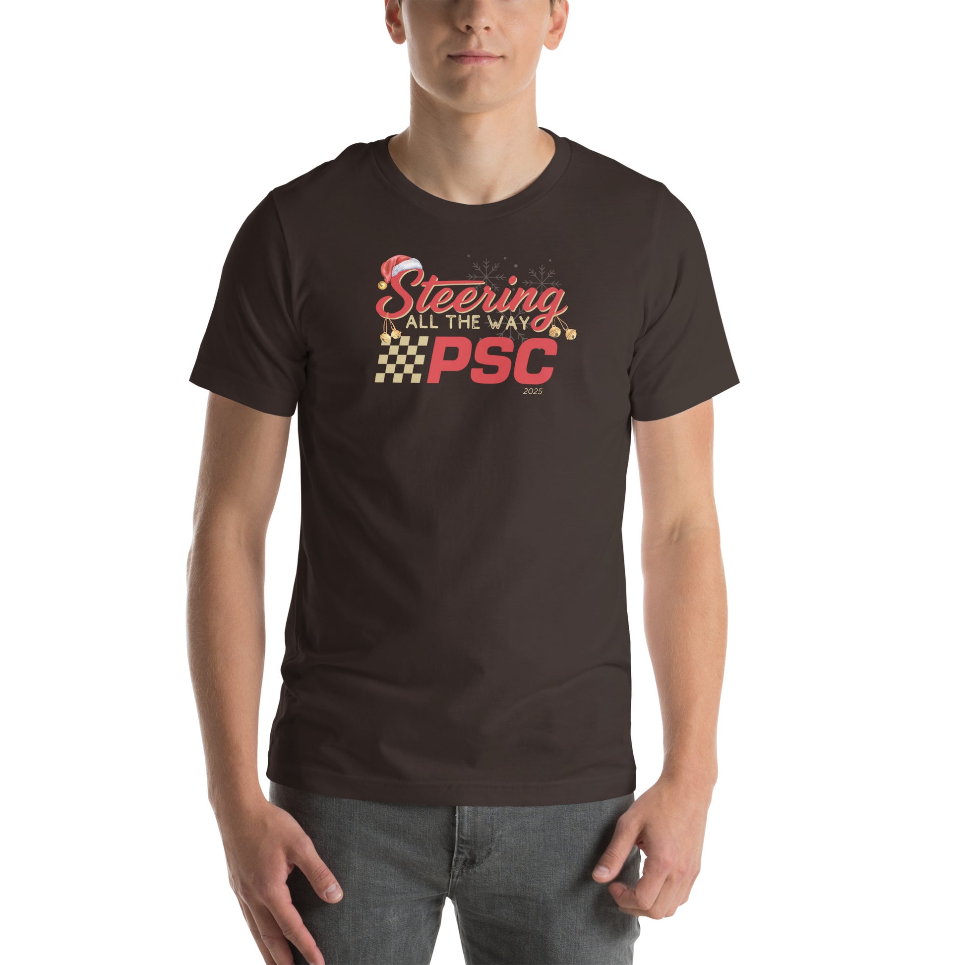 Front view of an adult model wearing a brown short-sleeve T-shirt with a PSC logo and the phrase ‘Steering All the Way PSC 2025’ printed across the chest in red and gold lettering. There is a Santa hat on the "S" in steering, bells handing off the bottom of the "S" and "g" in steering and translucent snowflakes in the background as well as "2025" right bottom corner offset.
