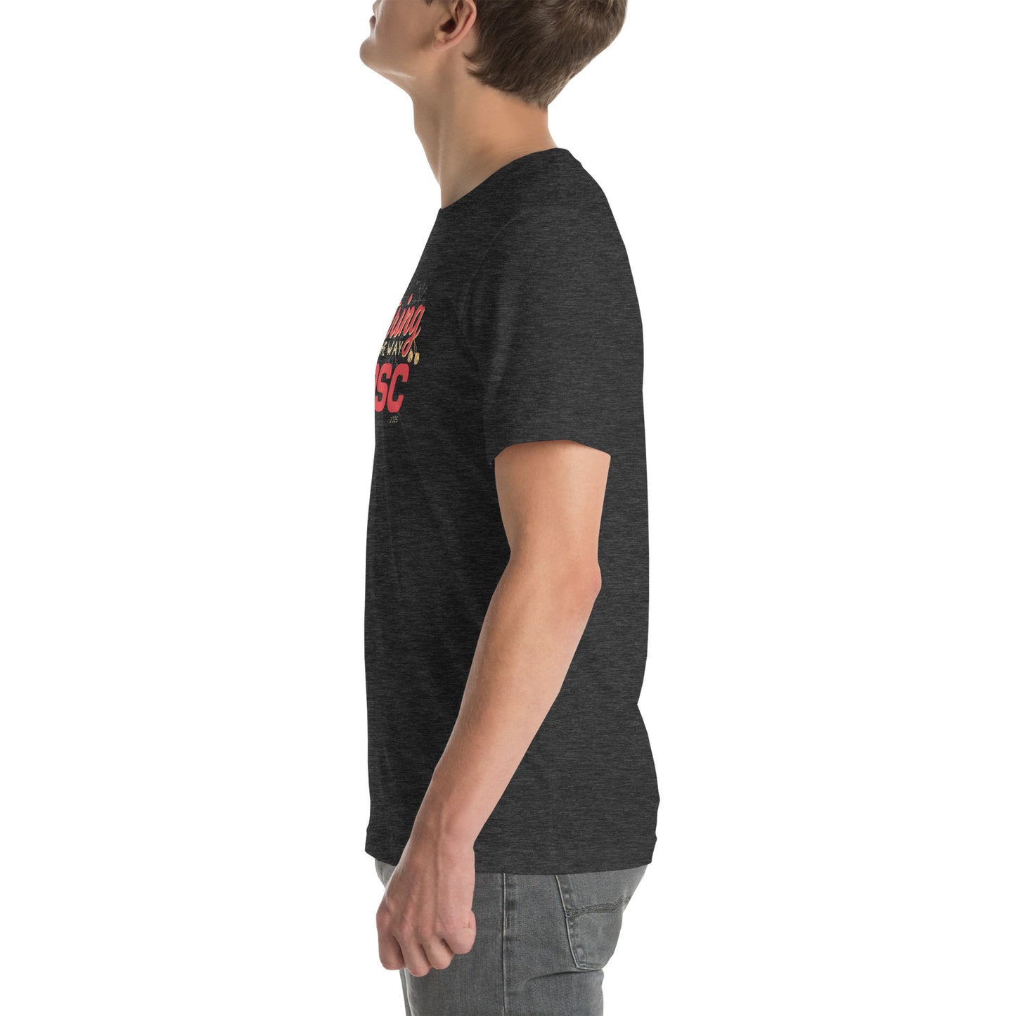 Side view of an adult model facing the left edge of the screen wearing a heather dark grey short-sleeve T-shirt you can see the edge of a red and gold design on the front of the shirt. The background is white.