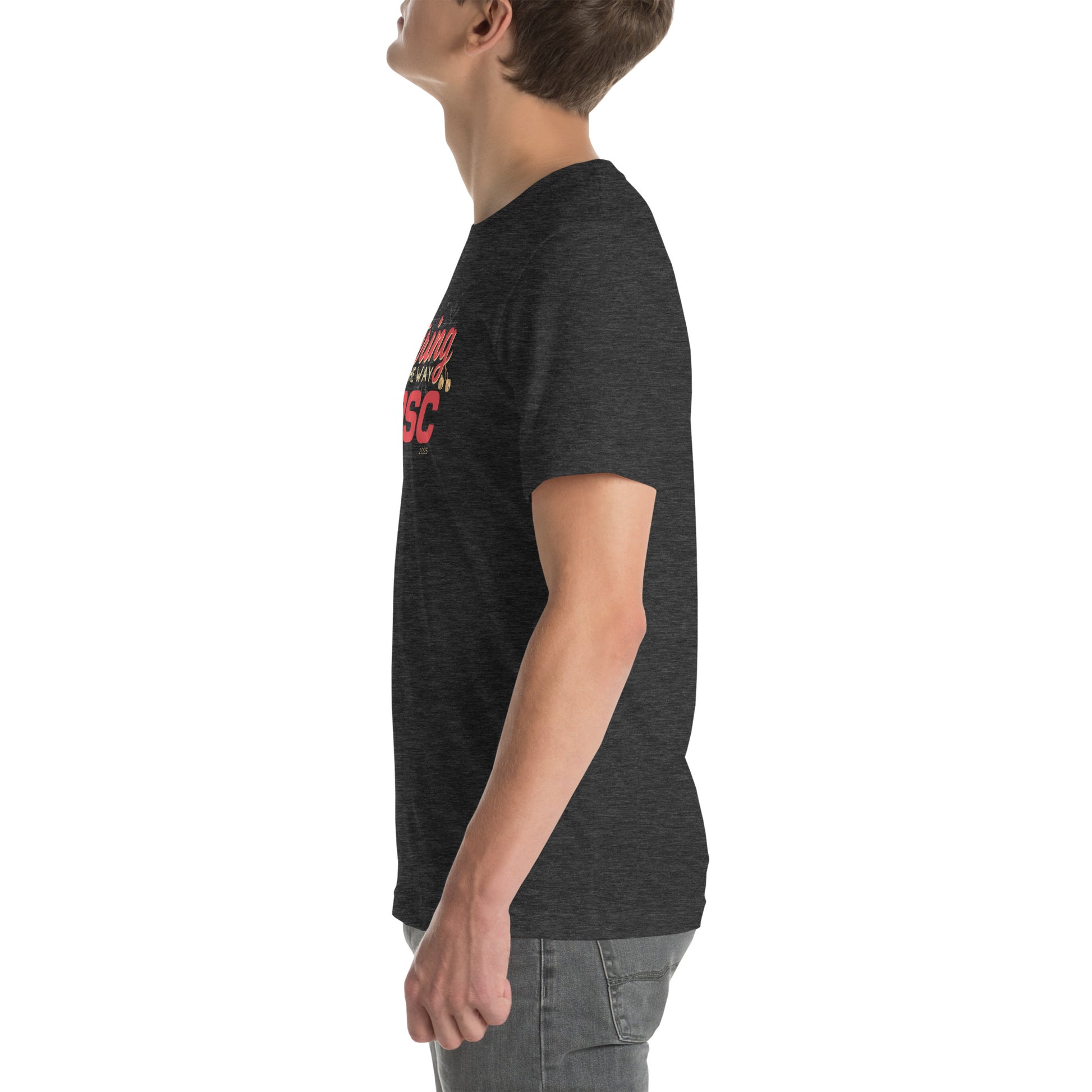 Side view of an adult model facing the left edge of the screen wearing a heather dark grey short-sleeve T-shirt you can see the edge of a red and gold design on the front of the shirt. The background is white.