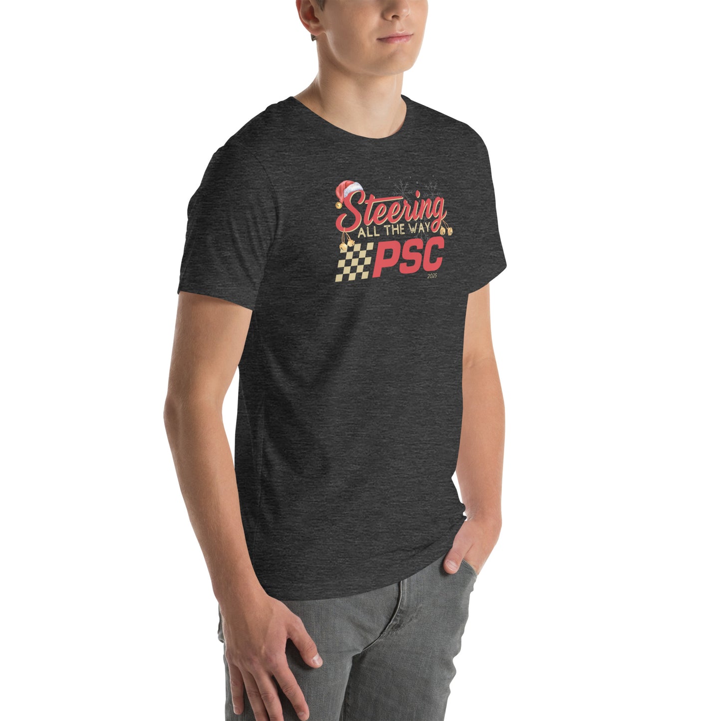 Angled front view of an adult model wearing a heather dark grey short-sleeve T-shirt with a PSC logo and the phrase ‘Steering All the Way PSC 2025’ printed across the chest in red and gold lettering. There is a Santa hat on the "S" in steering, bells handing off the bottom of the "S" and "g" in steering and translucent snowflakes in the background as well as "2025" right bottom corner offset. He is facing the right frame of the image.