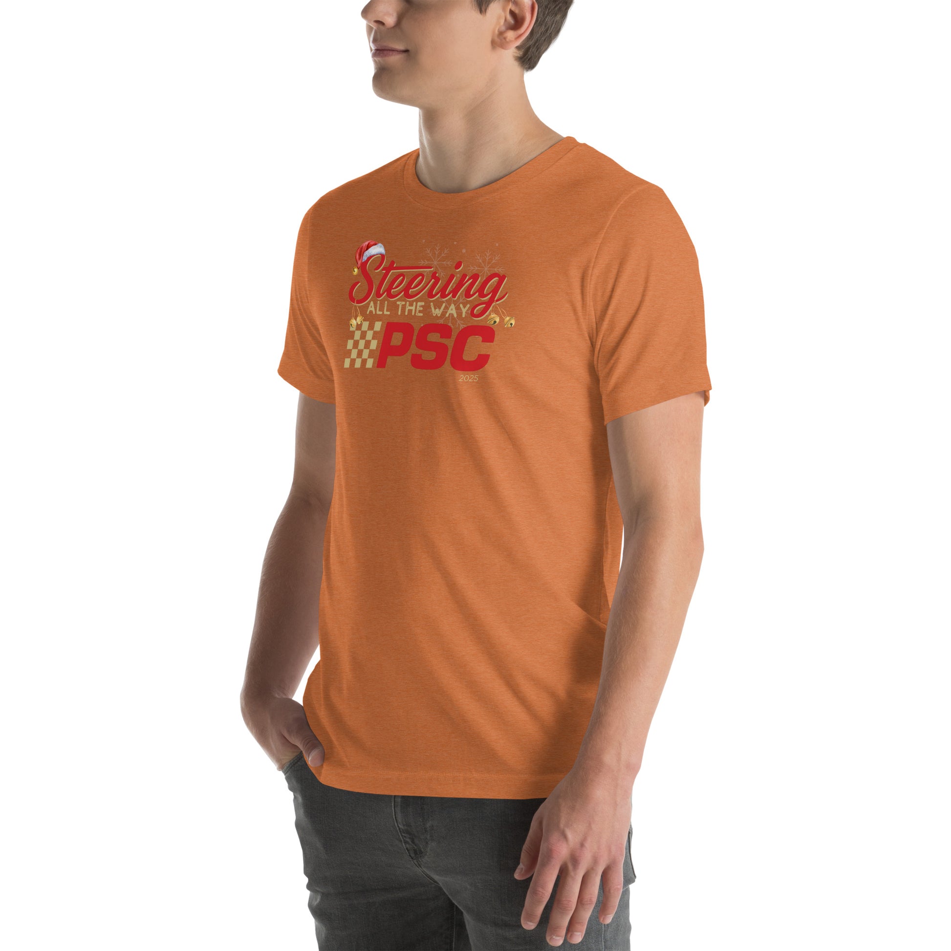 Angled front view of an adult model wearing a heather autumn orange short-sleeve T-shirt with a PSC logo and the phrase ‘Steering All the Way PSC 2025’ printed across the chest in red and gold lettering. There is a Santa hat on the "S" in steering, bells handing off the bottom of the "S" and "g" in steering and translucent snowflakes in the background as well as "2025" right bottom corner offset. He is facing the left frame of the image. 