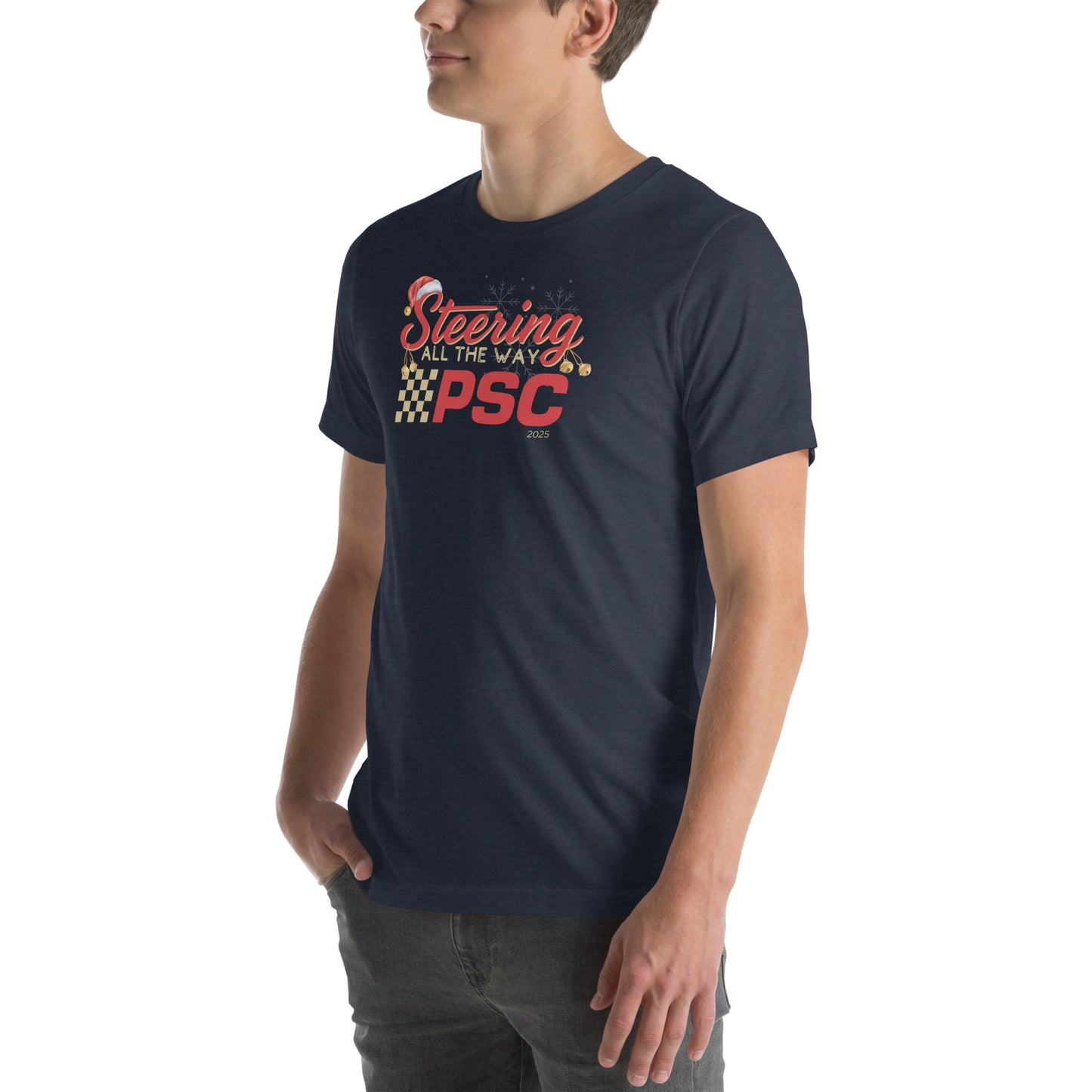 Angled front view of an adult model wearing a heather navy blue short-sleeve T-shirt with a PSC logo and the phrase ‘Steering All the Way PSC 2025’ printed across the chest in red and gold lettering. There is a Santa hat on the "S" in steering, bells handing off the bottom of the "S" and "g" in steering and translucent snowflakes in the background as well as "2025" right bottom corner offset. He is facing the left frame of the image.