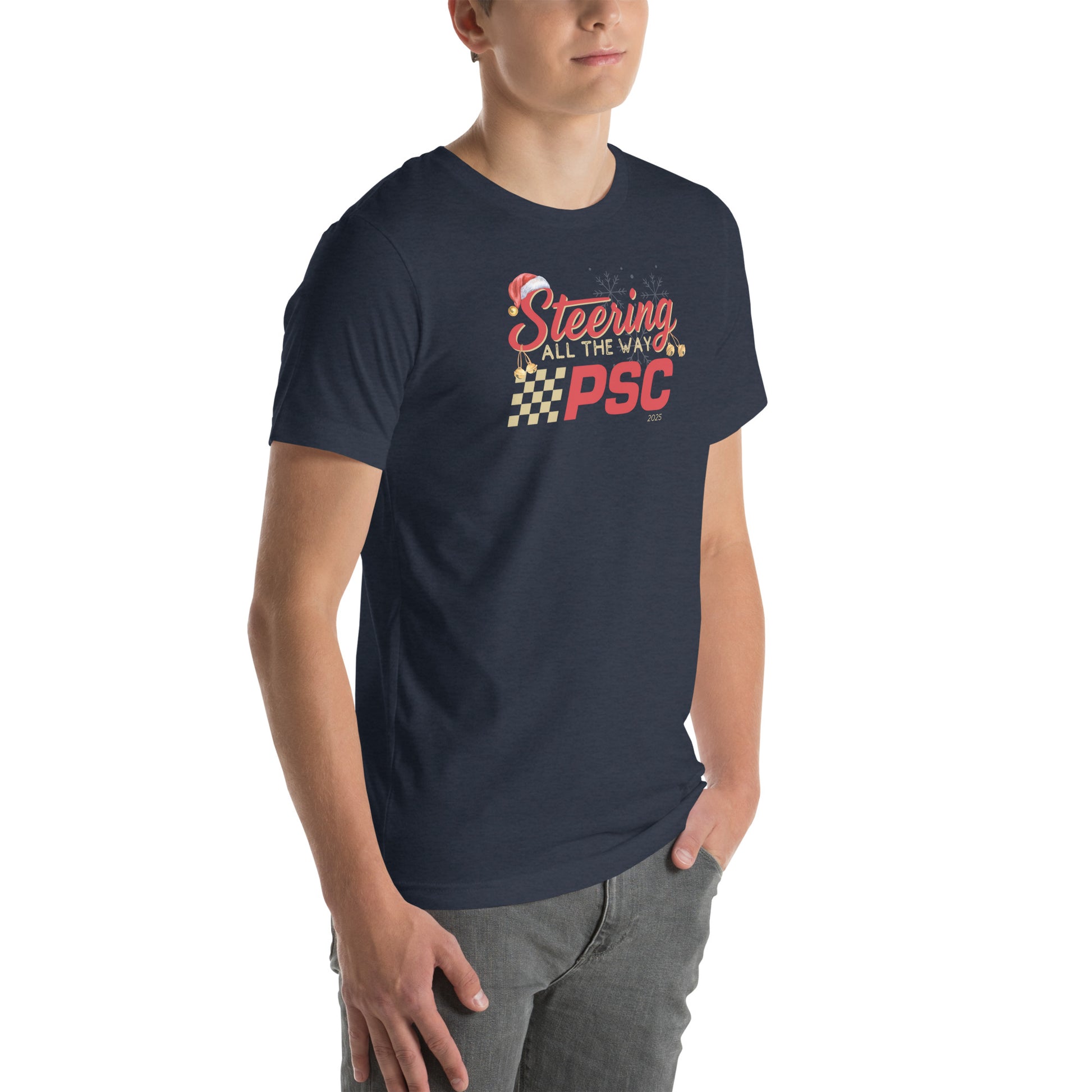 Angled front view of an adult model wearing a heather navy blue short-sleeve T-shirt with a PSC logo and the phrase ‘Steering All the Way PSC 2025’ printed across the chest in red and gold lettering. There is a Santa hat on the "S" in steering, bells handing off the bottom of the "S" and "g" in steering and translucent snowflakes in the background as well as "2025" right bottom corner offset. He is facing the right frame of the image.