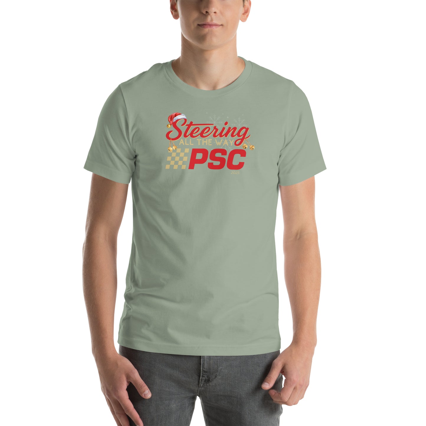 Front view of an adult model wearing a sage green short-sleeve T-shirt with a PSC logo and the phrase ‘Steering All the Way PSC 2025’ printed across the chest in red and gold lettering. There is a Santa hat on the "S" in steering, bells handing off the bottom of the "S" and "g" in steering and translucent snowflakes in the background as well as "2025" right bottom corner offset. 