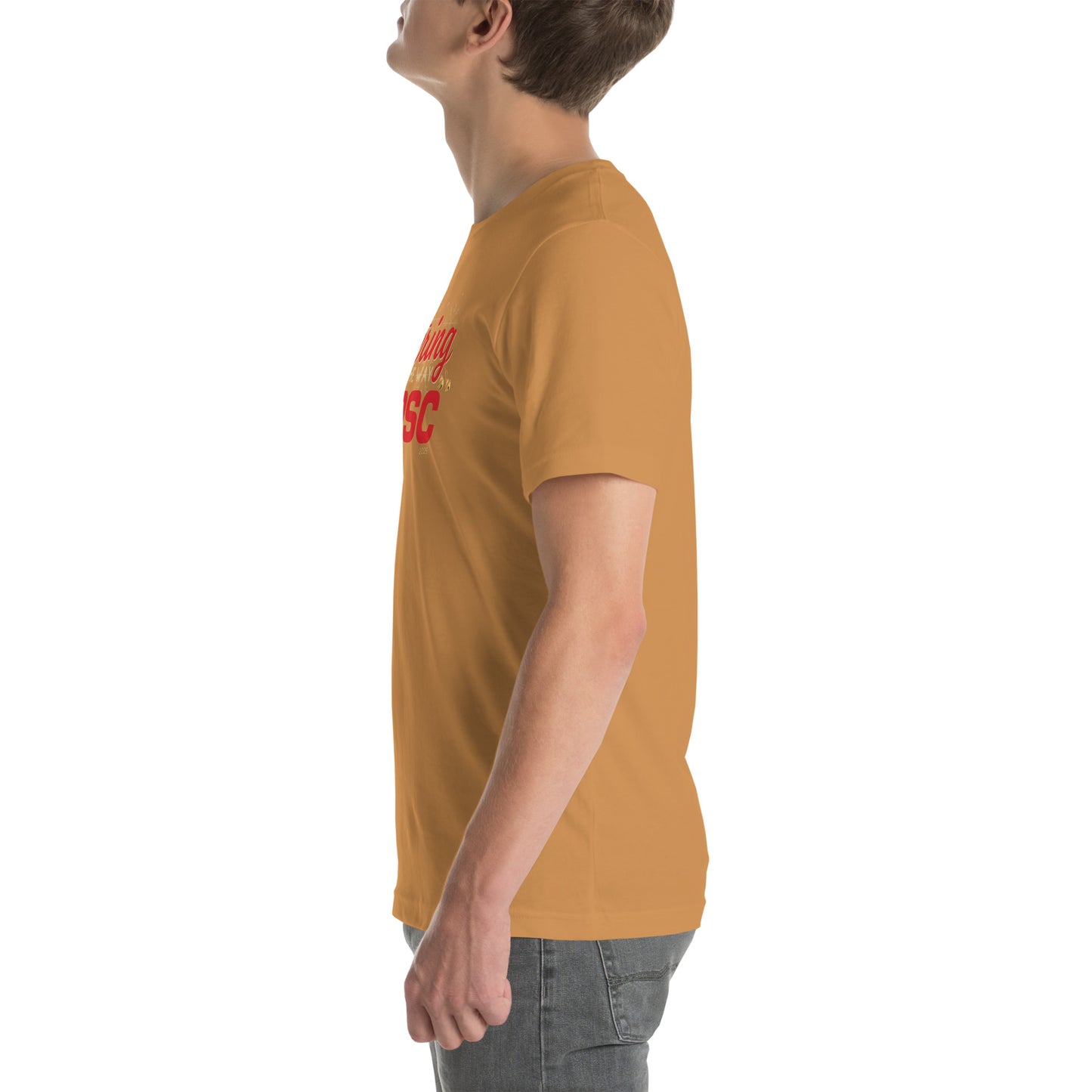 Side view of an adult model facing the left edge of the screen wearing a toast ornage-brown short-sleeve T-shirt you can see the edge of a red and gold design on the front of the shirt. The background is white. 