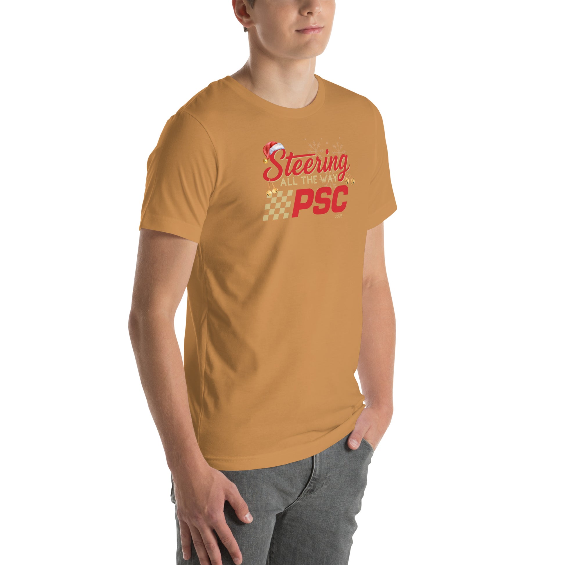 Angled front view of an adult model wearing a toast orange-brown short-sleeve T-shirt with a PSC logo and the phrase ‘Steering All the Way PSC 2025’ printed across the chest in red and gold lettering. There is a Santa hat on the "S" in steering, bells handing off the bottom of the "S" and "g" in steering and translucent snowflakes in the background as well as "2025" right bottom corner offset. He is facing the right frame of the image. 