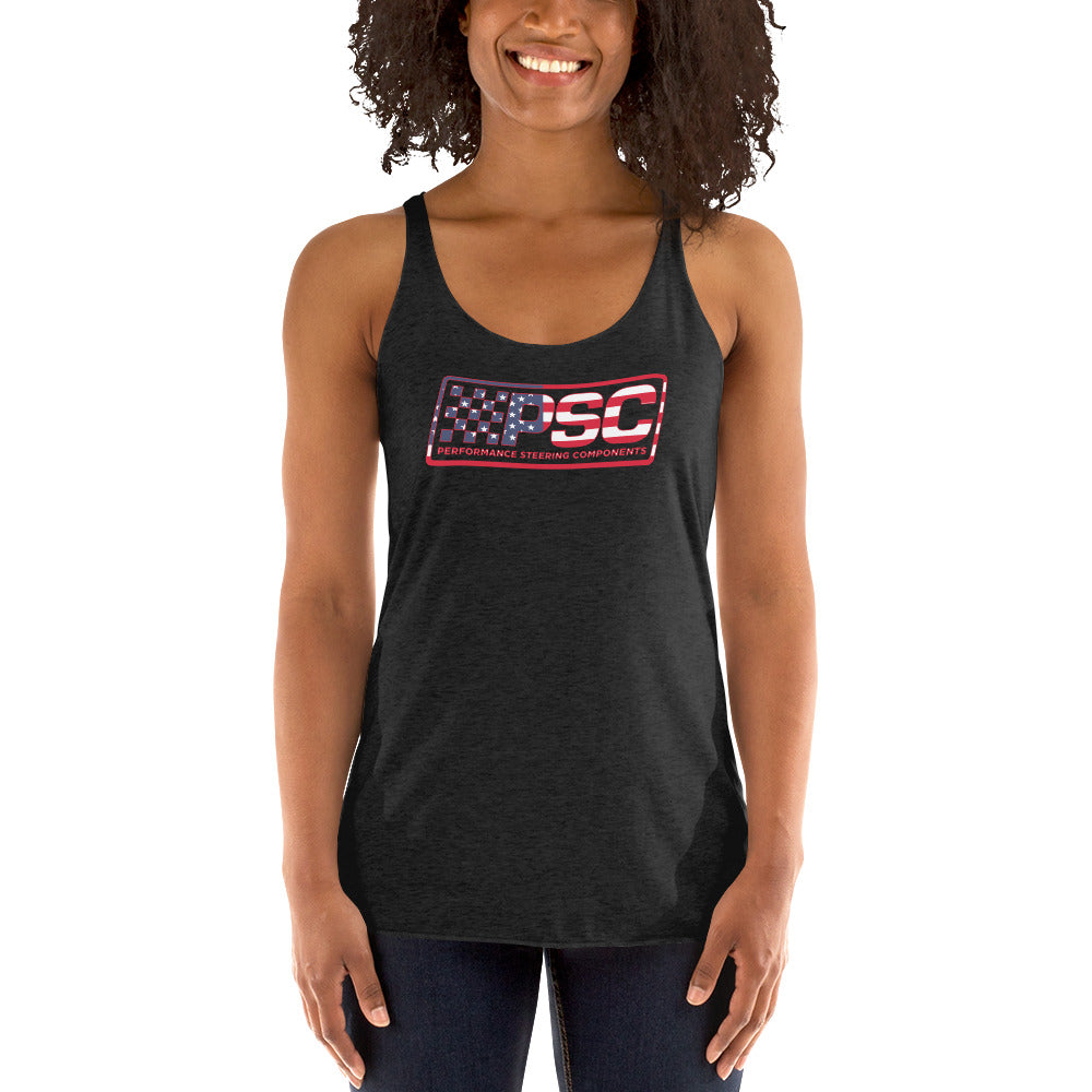 A woman is wearing a vintage turquoise women's racerback tank top with PSC Performance Steering Components logo featuring a patriotic overlay and red border on a white background. We can see her tank, dark jeans, curly black hair, arms and smile. 